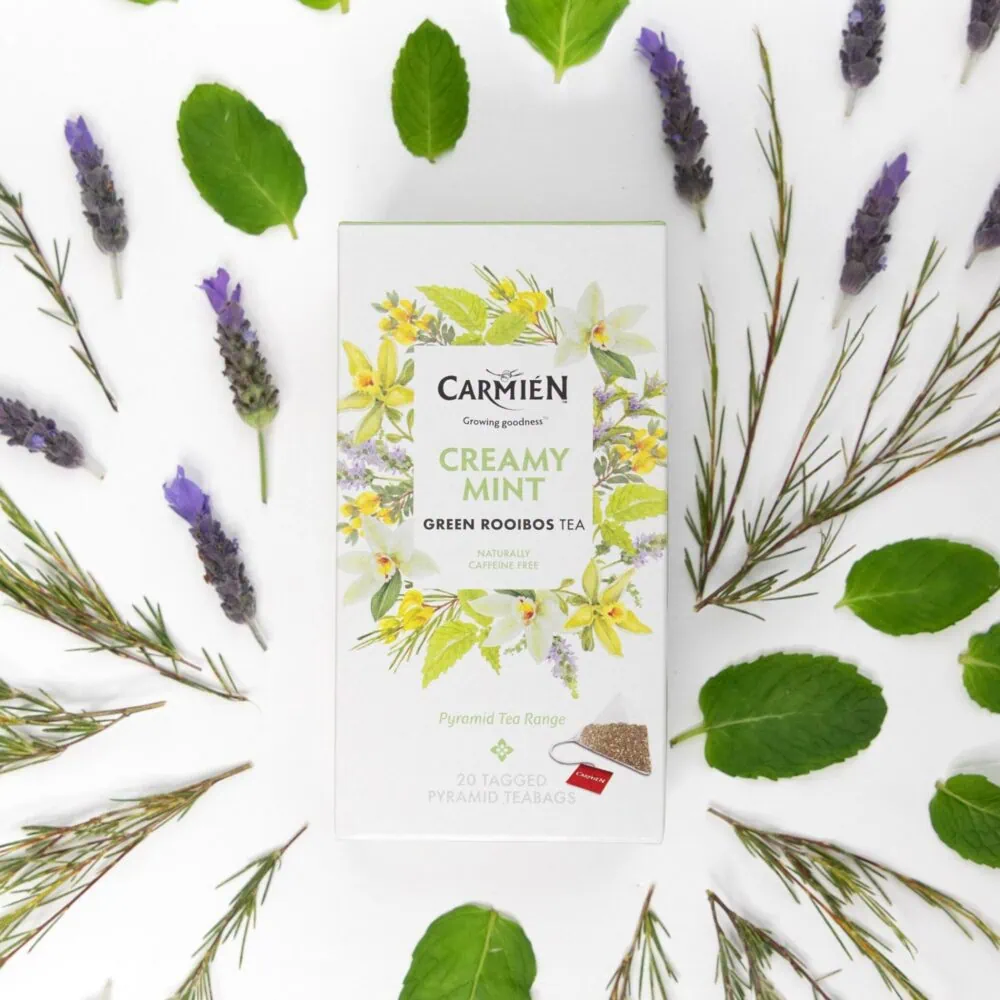 Carmién Creamy Mint Rooibos Tea box surrounded by fresh mint leaves and lavender sprigs, highlighting the natural ingredients and premium quality of this herbal tea blend.