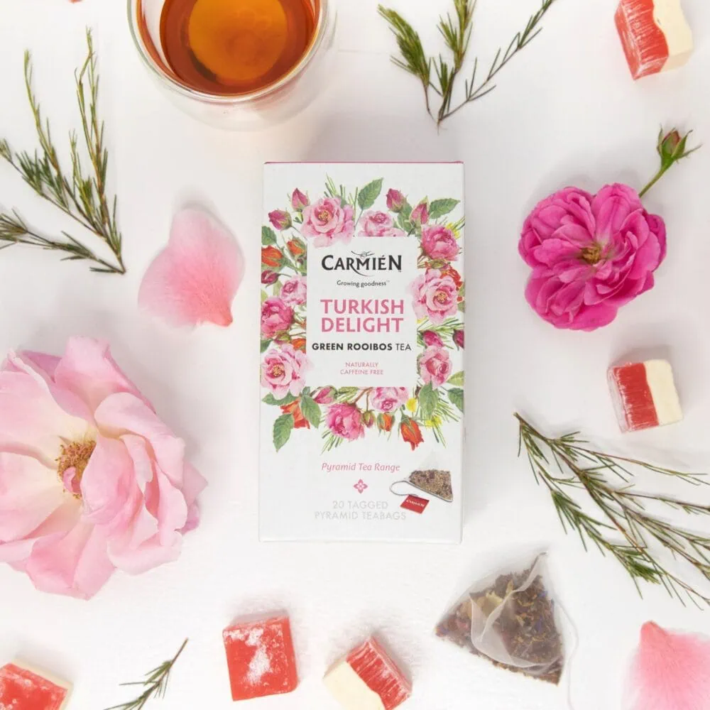 Carmién Turkish Delight Rooibos tea box with pyramid teabags surrounded by flowers and tea treats, highlighting the premium rooibos tea blend for e-commerce.