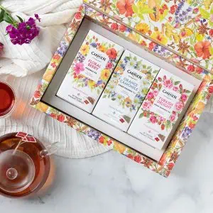 Vibrant herbal tea gift box featuring Carmién Tea's floral, orange chamomile, and Turkish delight green rooibos tea varieties, beautifully packaged with botanical illustrations.