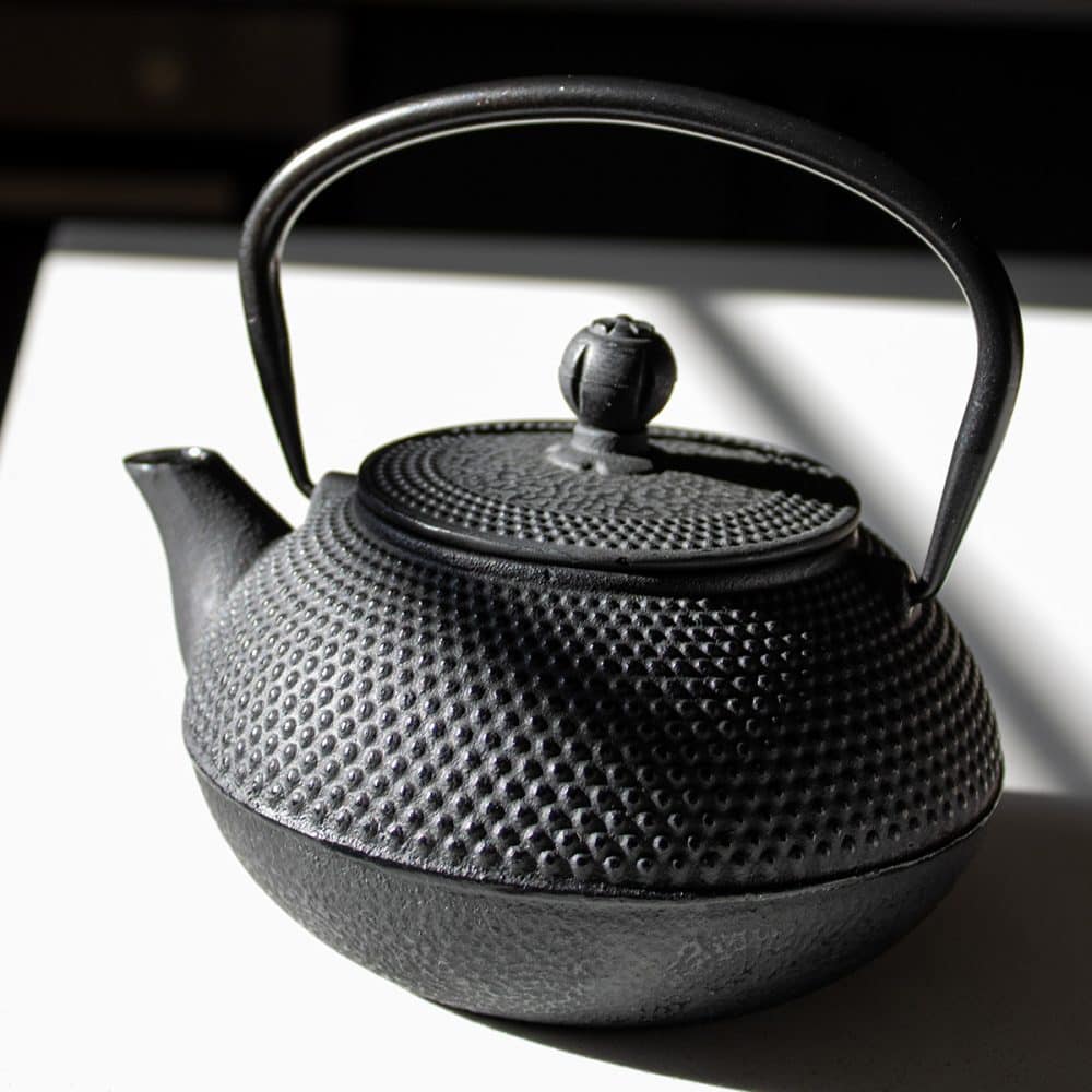 Black cast iron teapot for brewing tea.