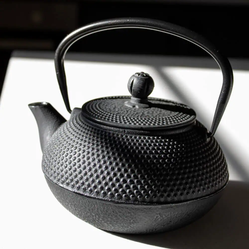 Black cast iron teapot for brewing tea.