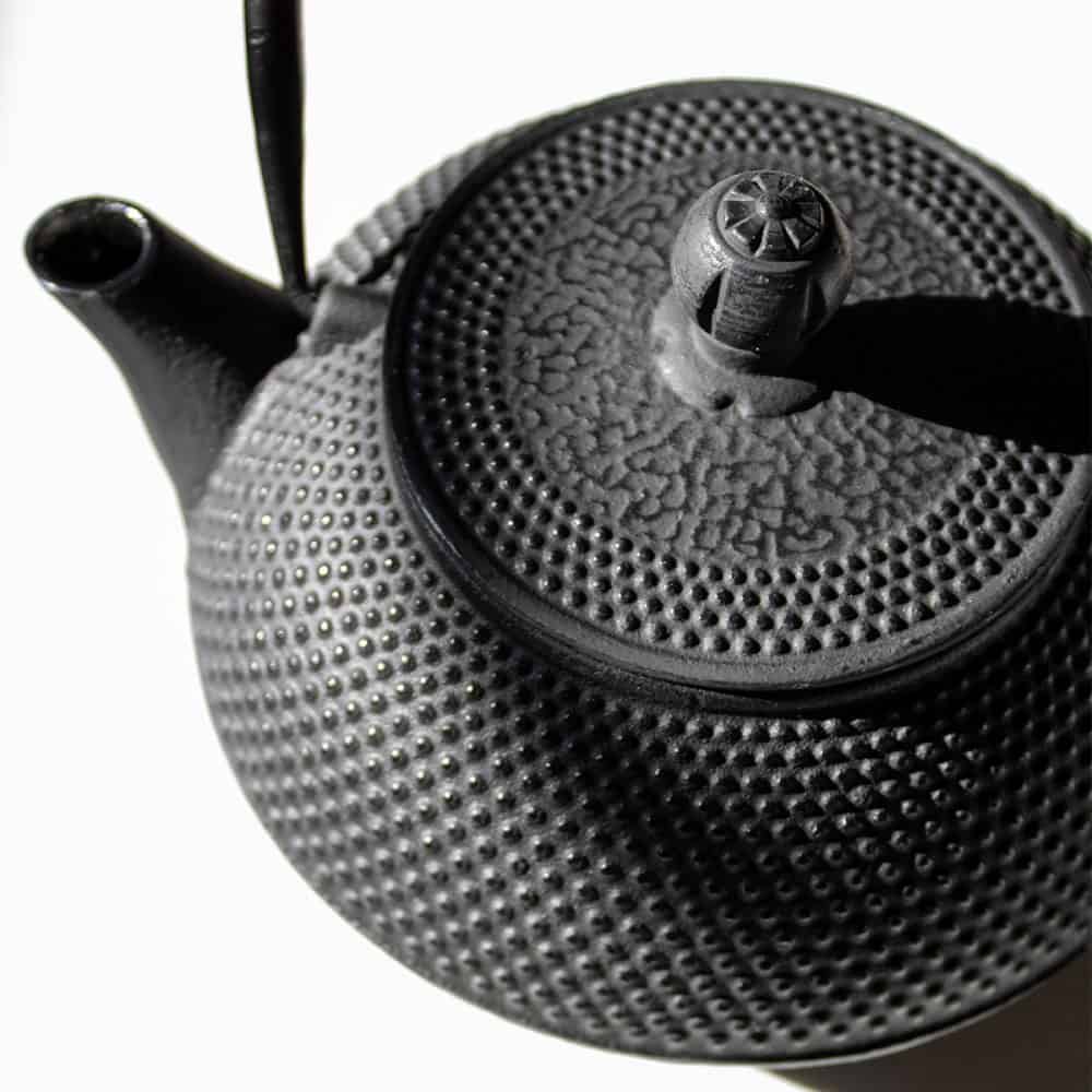 Black cast iron teapot for brewing traditional tea, featuring a textured surface and durable design. Perfect for tea enthusiasts seeking quality and style in their tea-making experience.