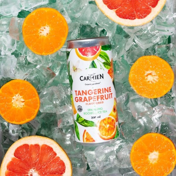 Refreshing tangerine grapefruit rooibos iced tea can with slices of citrus fruits and ice cubes. Perfect for summer, highlighting natural flavors and wellness benefits of Carmién Tea products.