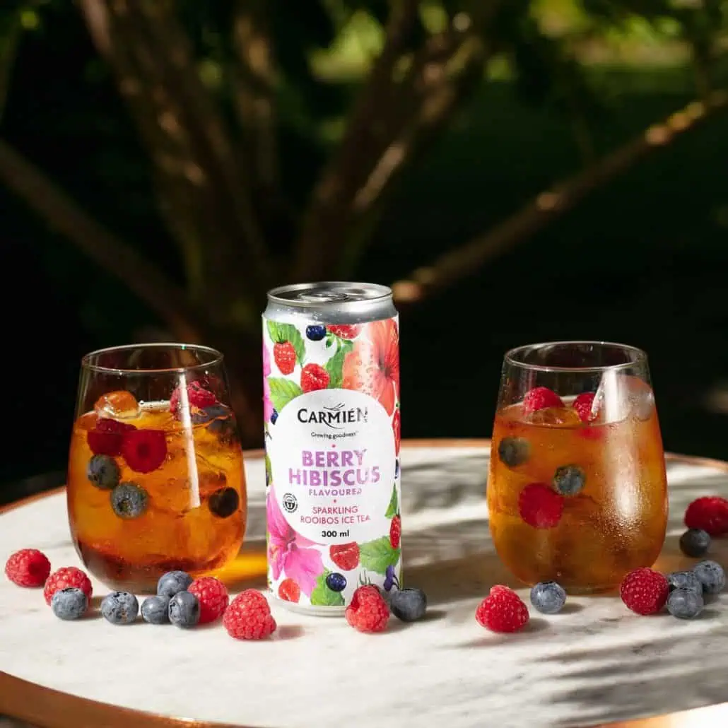 Fresh Berry Hibiscus flavoured Rooibos iced tea in sparkling cans and glasses, garnished with real berries, highlighting South African herbal tea and wellness products.