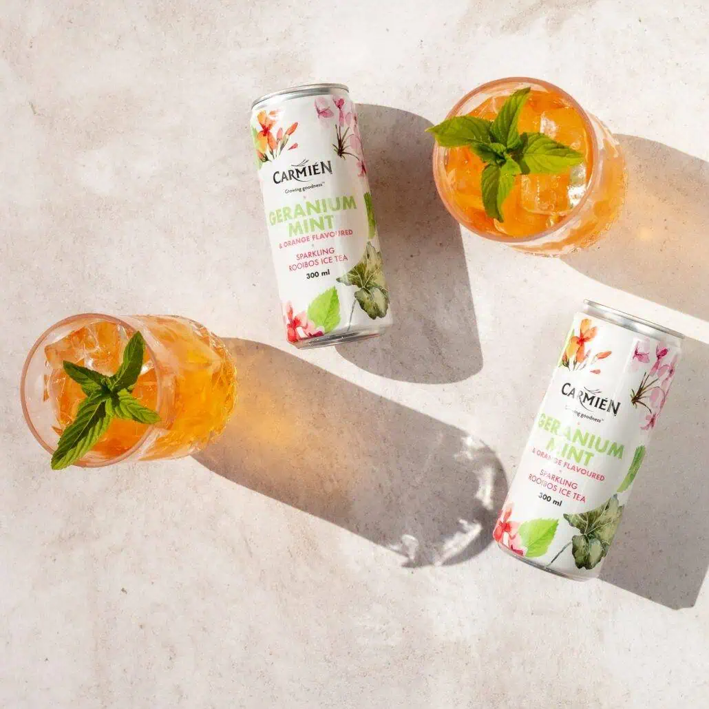 Refreshing Carmién Geranium Mint Rooibos Ice Tea cans with mint garnish, perfect for a cooling summer drink, highlighting natural ingredients and vibrant citrus flavours.