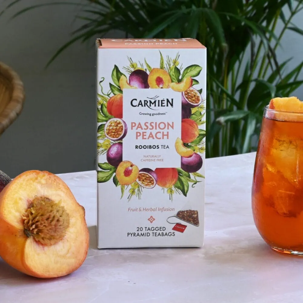 Carmién Passion Peach Rooibos Tea box with fresh peach and iced tea glass, highlighting the fruity and herbal infusion for tea lovers.