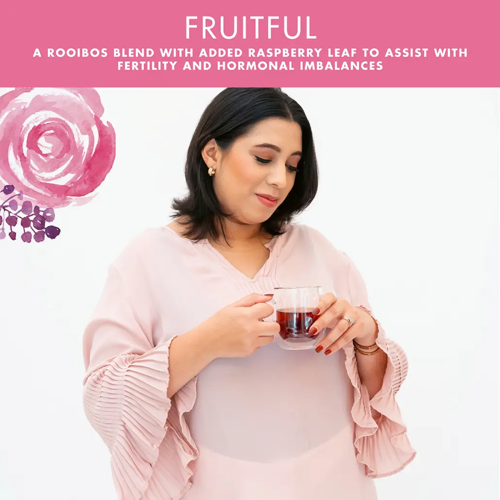 A woman smiles while drinking Carmien Fruitful caffeine free herbal Rooibos tea with Raspberry Leaf