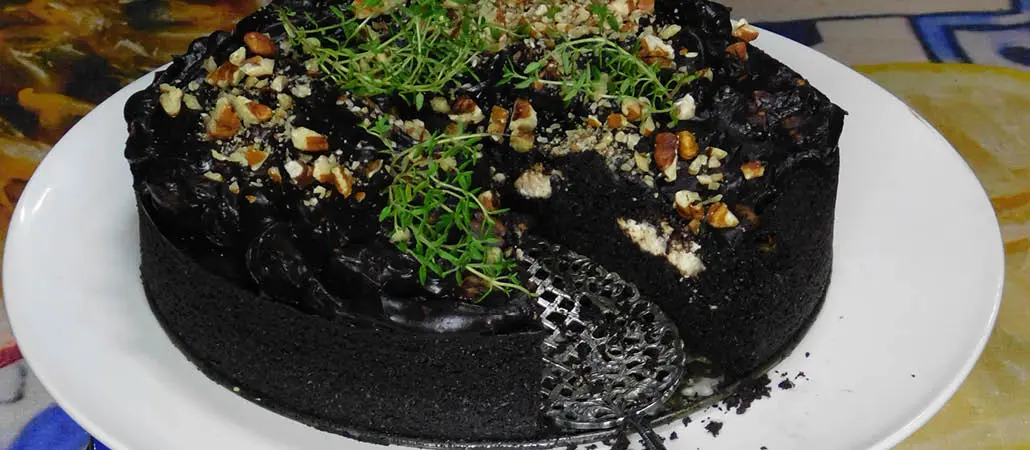 Rich black forest cake topped with crushed nuts and fresh herbs, served on a white plate, showcasing a decadent dessert filled with layers of cream and cherries, perfect for special occasions and tea breaks.