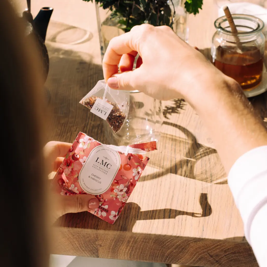 LMC Cherry & Hibiscus Carmién Tea being prepared with dried herbs on a rustic wooden table in South Africa.