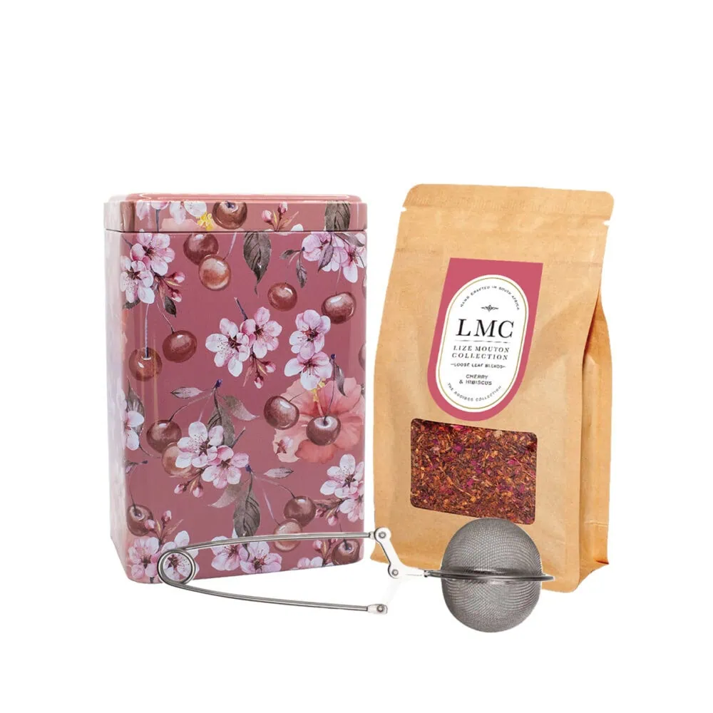 Bright pink floral tea tin with cherry blossom design, containing Carmién Tea herbal blend, accompanied by a tea infuser and a bag of dried herbal tea leaves, perfect for a relaxing South African herb.