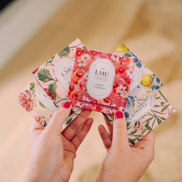 LMC Carmién Tea Cherry & Hibiscus compostable pyramid teabags showcasing vibrant floral and fruit designs, promoting South African herbal tea with organic, eco-friendly packaging for health-conscious consumers.