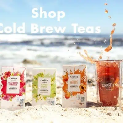Vegan Cold Brew Tea packs on a beach, promoting Carmién Tea's refreshing iced herbal teas, including cranberry hibiscus, apple mint, and apricot blossom, perfect for summer relaxation.