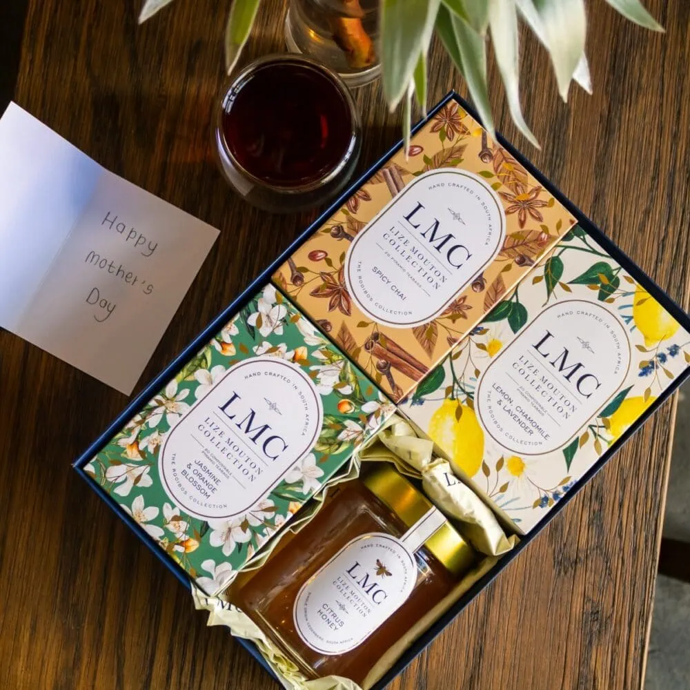 Elegant Carmién Tea LMC gift box with honey and tea bags, perfect for gifting. Features vibrant floral packaging and a jar of honey, ideal for tea lovers.