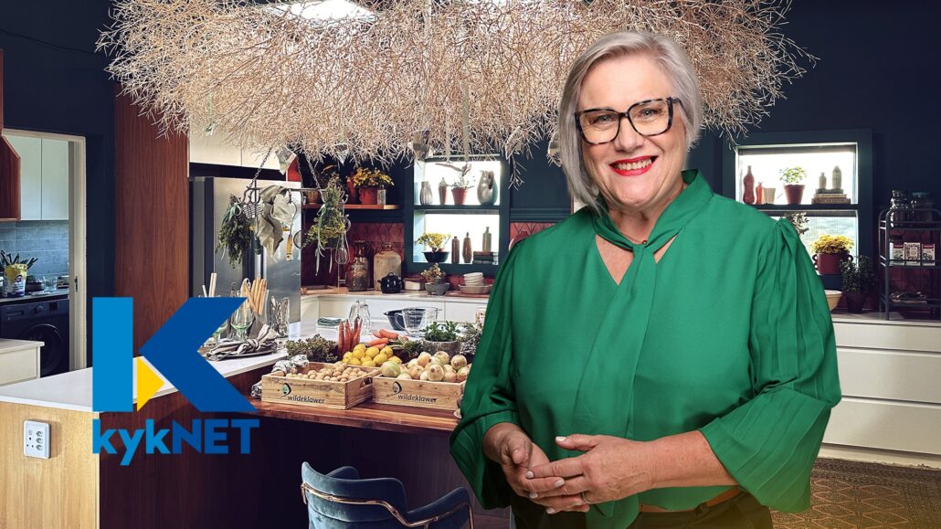 Elegant woman enjoying Carmién Tea in a cozy kitchen setting, highlighting the natural herbal tea brand.