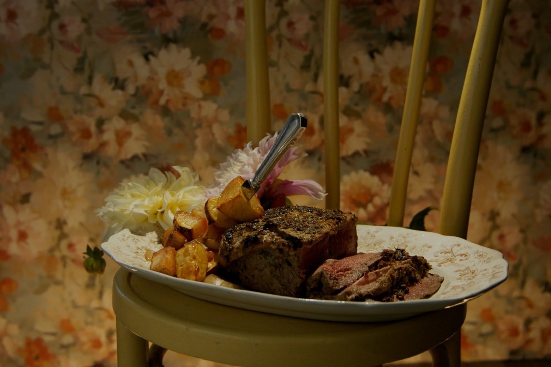 Cooked curried beef loin served with rooibos tea and roasted vegetables on a decorative plate.