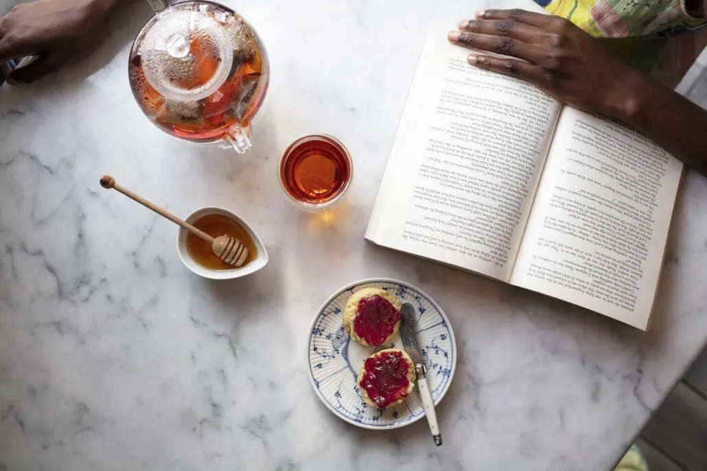 Carmién Rooibos tea with honey and snacks on a marble table, promoting healthy, natural rooibos tea blends.